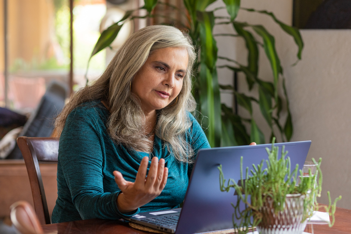 Older woman having a video counselling session at home on her laptop.