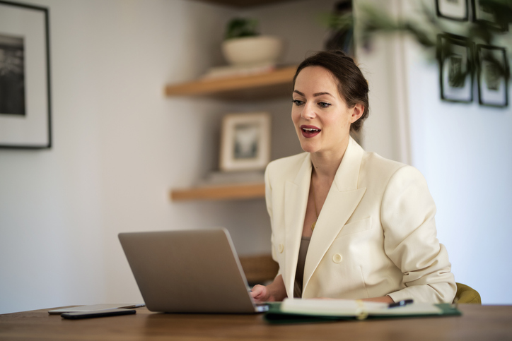 Professional woman attending an online counselling session from her home office via laptop.