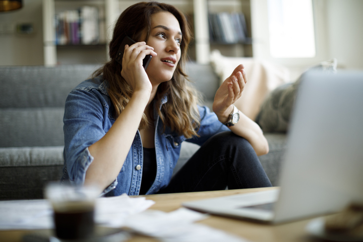 Young woman at home talking to her counsellor on a mobile phone
