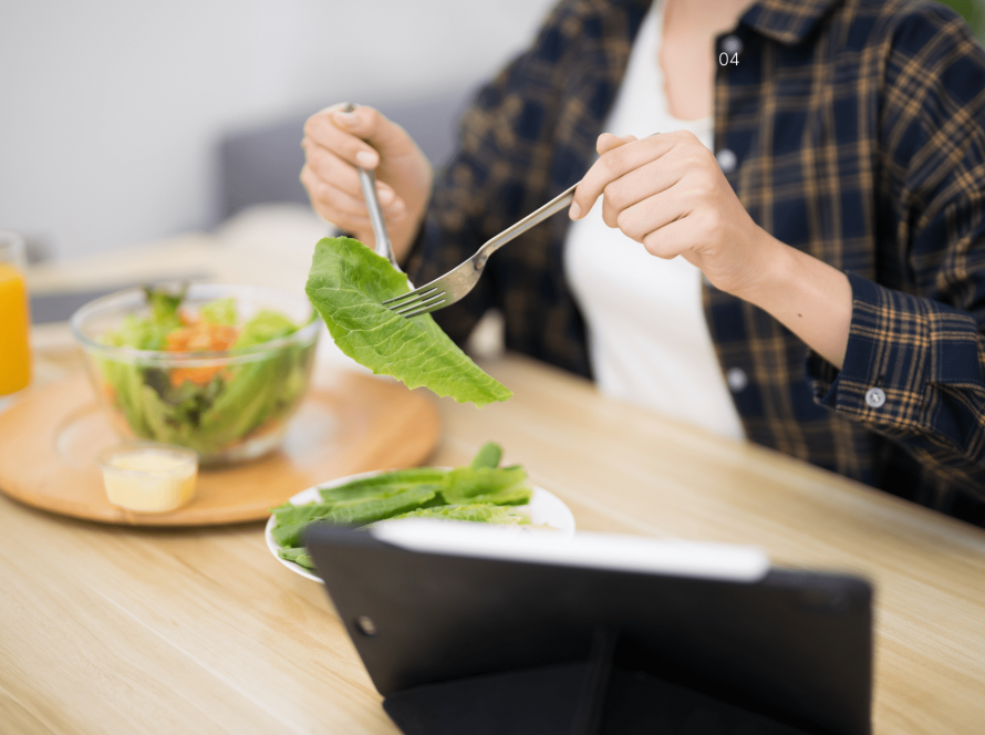Woman sitting at a table mindfully eating fresh nutritious food, reflecting the gut-brain connection and emotional wellbeing.