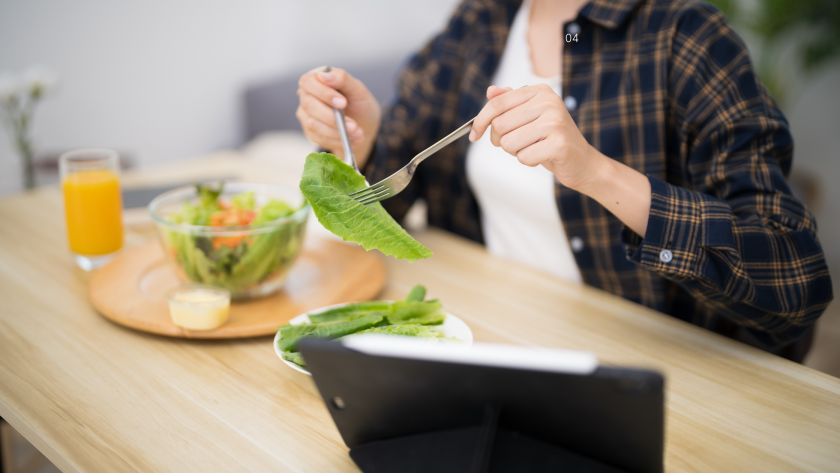 Woman sitting at a table mindfully eating fresh nutritious food, reflecting the gut-brain connection and emotional wellbeing