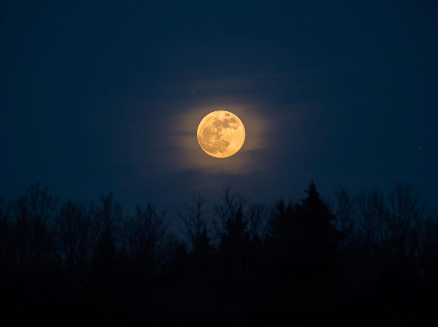 A softly glowing full moon in a dark blue winter sky, symbolising the Long Night Moon and the darker days of winter.