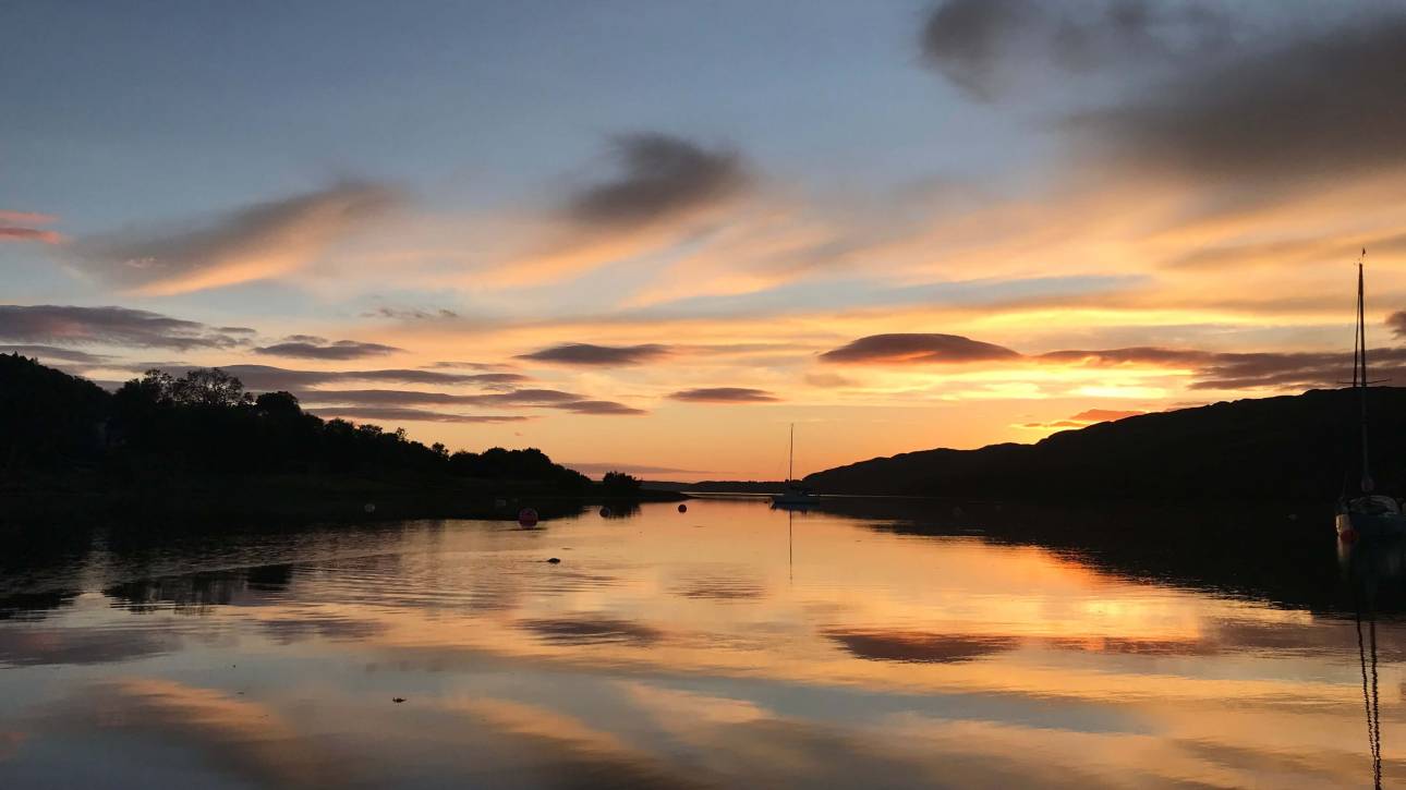 Sunset over an estuary with soft light and shadow, looking towards the horizon, reflecting uncertainty and transition.