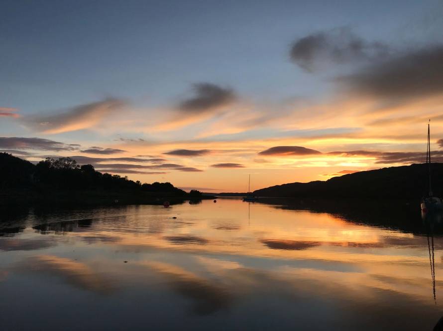 Sunset over an estuary with soft light and shadow, looking towards the horizon, reflecting uncertainty and transition.