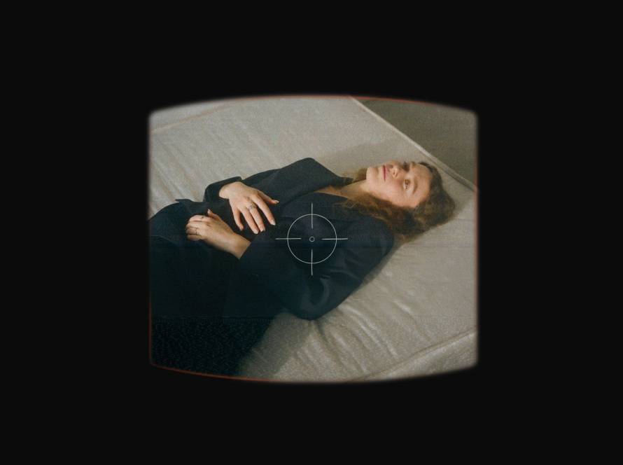 Woman in suit lying on bed looking reflective and sad, representing internal conflict with self