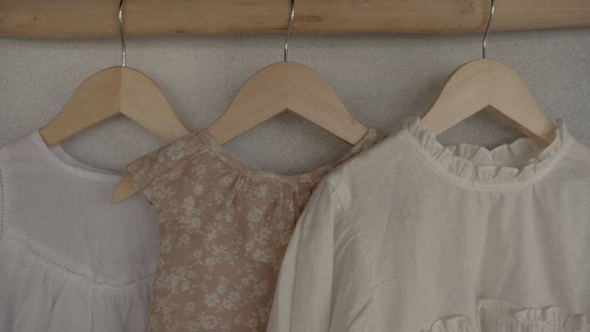 Neutral colored clothes hanging on wooden rail - spring wardrobe anxiety