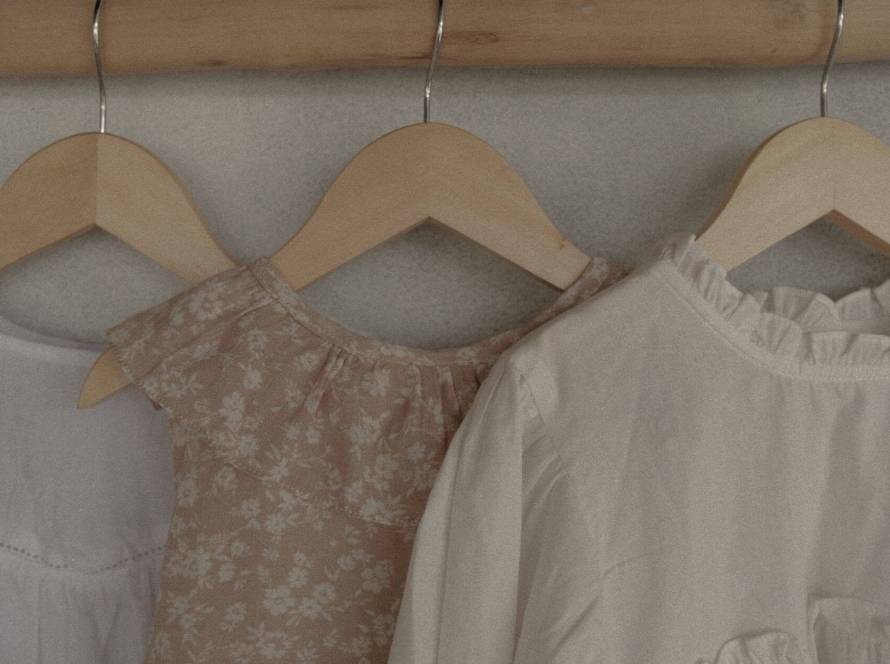 Neutral colored clothes hanging on wooden rail - spring wardrobe anxiety