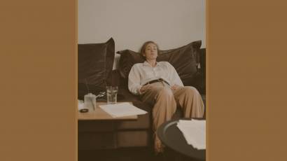 A woman resting on a dark sofa surrounded by papers — burnout vulnerability explored by Karen Toms therapist and counsellor
