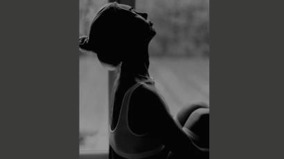 A woman in silhouette with face tilted upward, partially in shadow, representing the feeling of being unseen and invisible despite being present.
