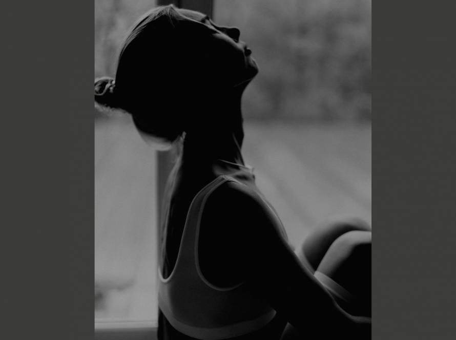 A woman in silhouette with face tilted upward, partially in shadow, representing the feeling of being unseen and invisible despite being present.