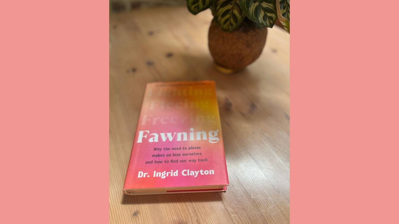 Personal photograph of Fawning by Dr Ingrid Clayton on a wooden desk beside a plant in warm spring light.