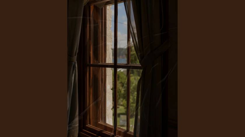 A view through a window with soft curtain detail, illustrating the suspended state of burnout recovery