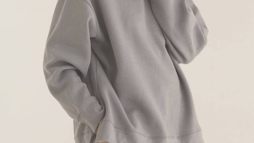 A figure in an oversized neutral sweatshirt, partially hidden, illustrating clothes as disguise