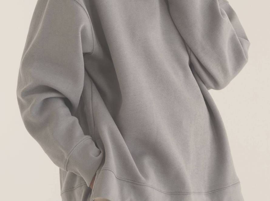 A figure in an oversized neutral sweatshirt, partially hidden, illustrating clothes as disguise