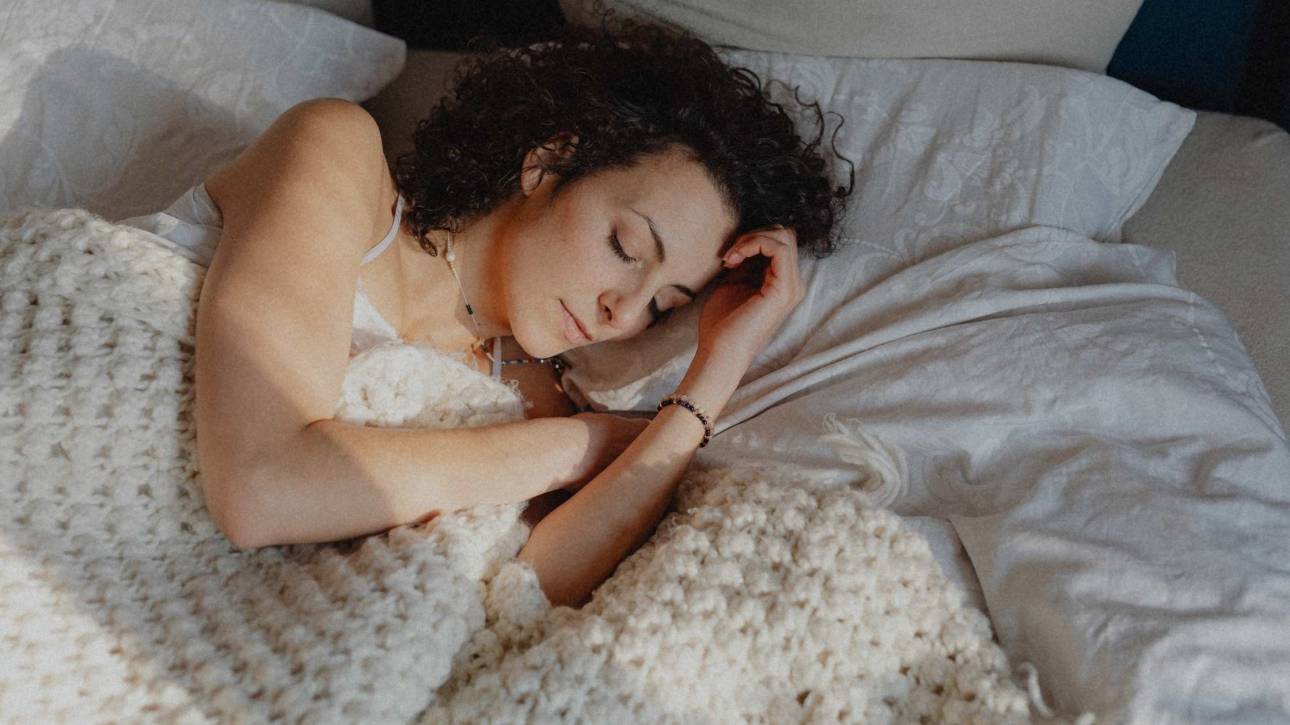 A woman resting in warm light, head bowed, illustrating a post about burnout and perfectionism