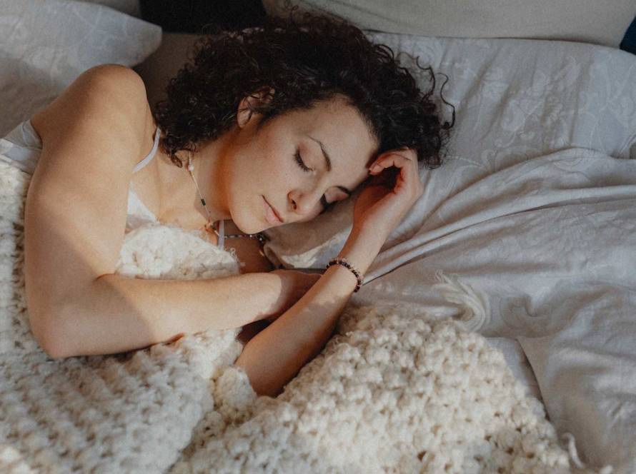 A woman resting in warm light, head bowed, illustrating a post about burnout and perfectionism
