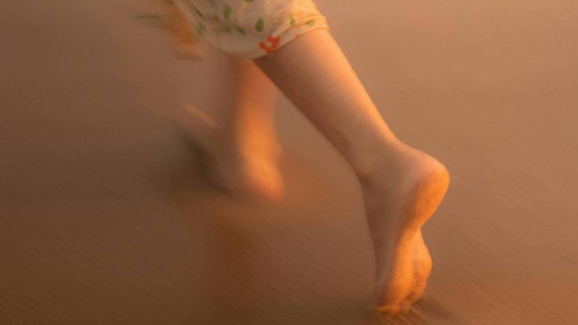 Bare feet in motion against warm golden light, evoking the free, flowing quality of moving meditation