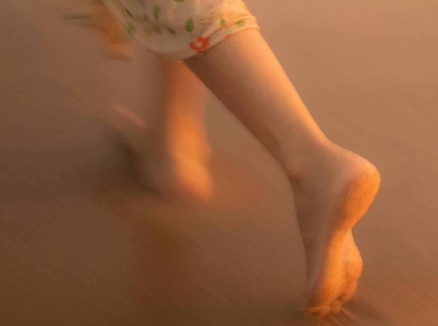 Bare feet in motion against warm golden light, evoking the free, flowing quality of moving meditation