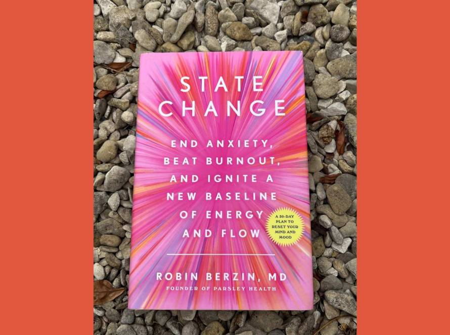 Copy of State Change by Robin Berzin resting on grey gravel, framed by warm orange side panels