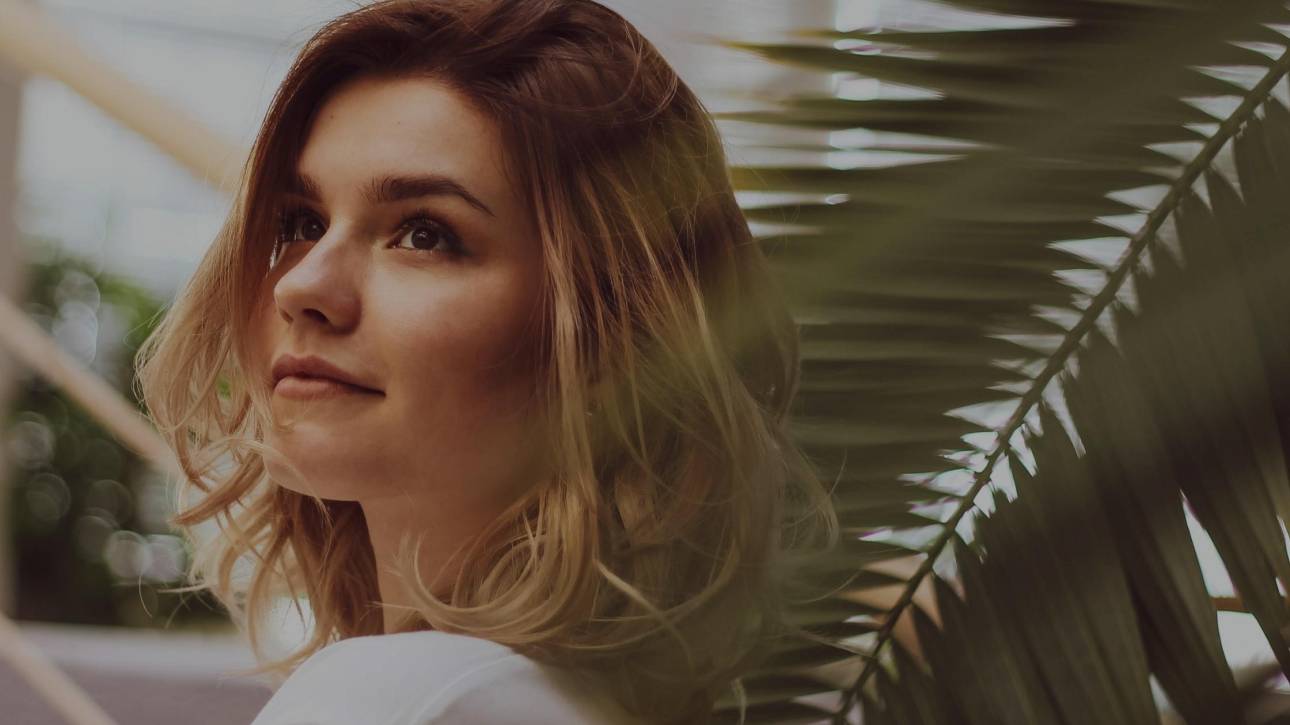 Woman gazing upward and outward in warm contemplative light, reflecting on who her perfectionism performs for