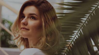 Woman gazing upward and outward in warm contemplative light, reflecting on who her perfectionism performs for
