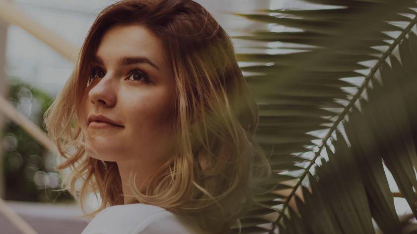 Woman gazing upward and outward in warm contemplative light, reflecting on who her perfectionism performs for