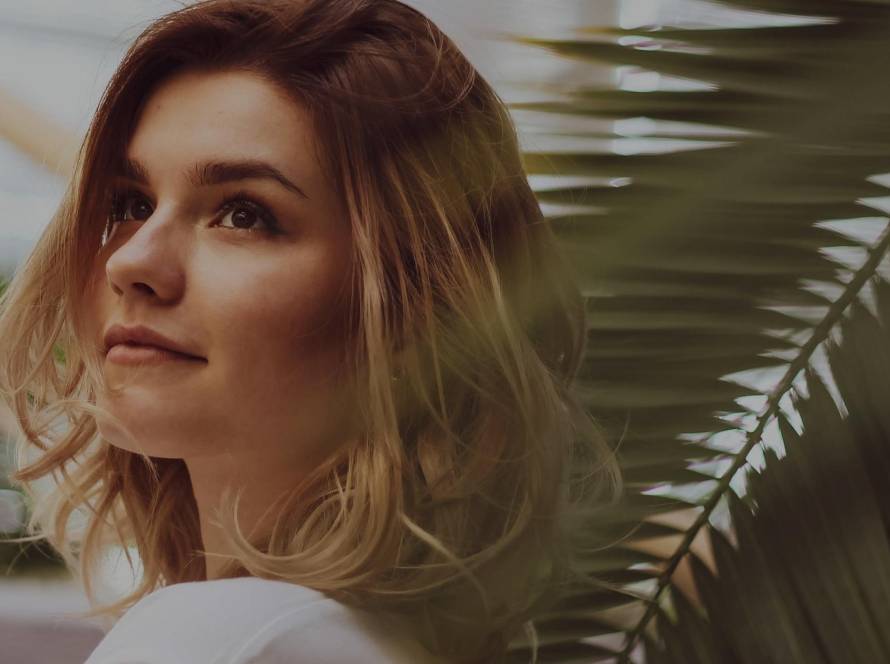 Woman gazing upward and outward in warm contemplative light, reflecting on who her perfectionism performs for
